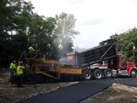 A man operates a machine to pour the pavement.