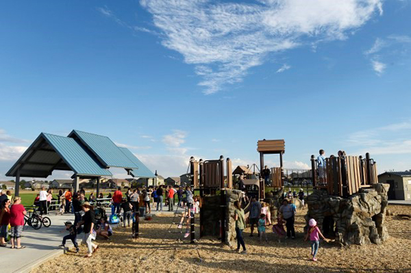 People gathered, bicycling and playing on park equipment