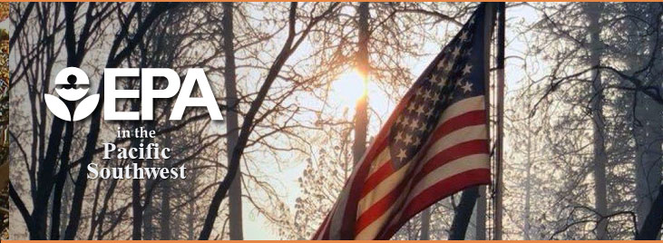 Image of U.S. flag with smoke and trees in background