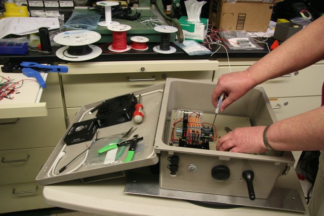 EPA researcher looks over internal components of sensor package, which includes a commercial low-cost air sensor, to measure fine particulate matter (PM2.5), black carbon, and meteorological conditions.