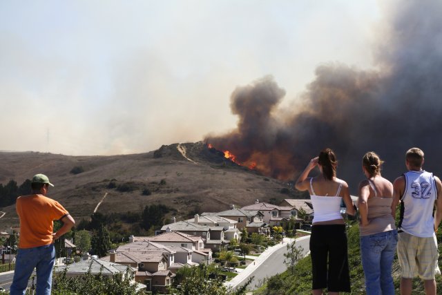 Image of 4 people on a ridge watching a wildfire burn in the distance