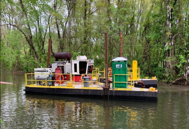 Small boat with dredging equipment mounted on it