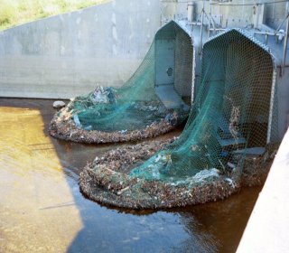 Net's surrounding large water oufall's full of trash