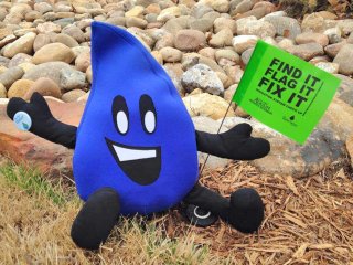 Flo, the WaterSense mascot, holding a flag over a sprinker head.