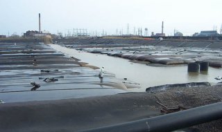 Photo of Contaminated sediment is pumped into large fabric tubes to drain/separate water from the sediment. 