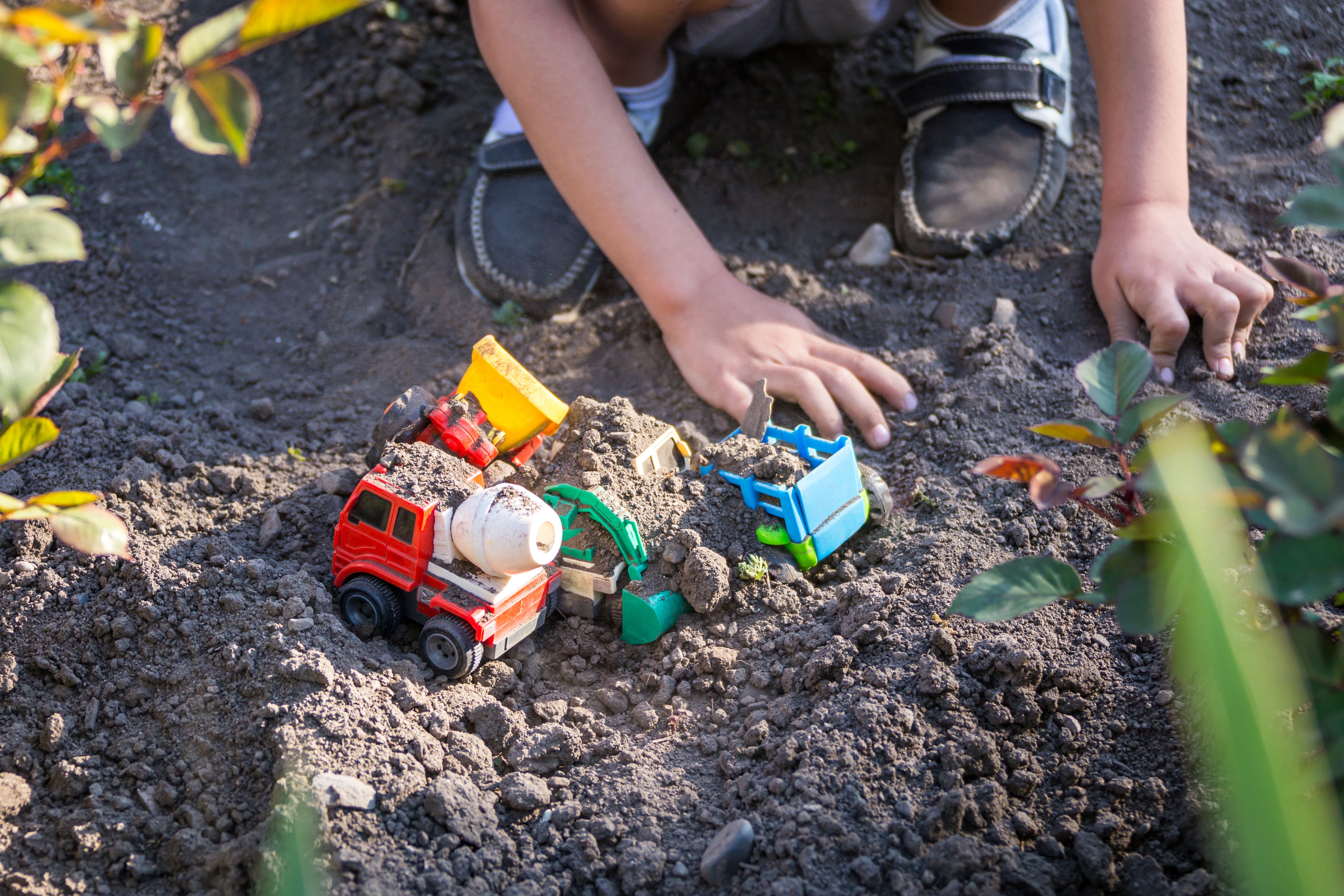 child playing with trucks in the dirt