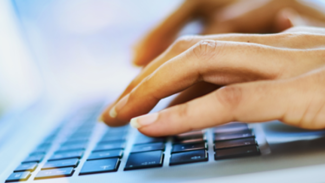 Hands typing on a laptop computer.