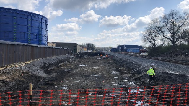 Excavated pit in the center, with blue tank on the let and railroad tracks to the right.