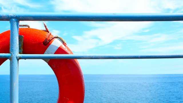 view looking seaward from the deck of a vessel of a life ring on the rail of the vessel