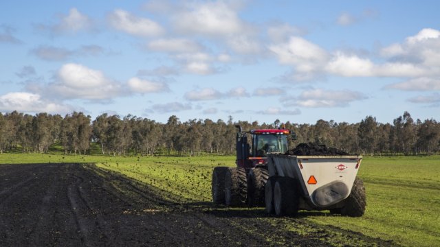 Tractor spreads biosolids on field of crops