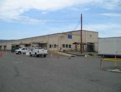 A parking lot, trucks, traffic cones, and building.