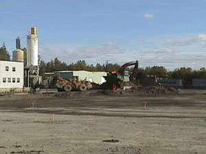 A dirt area with machinery and buildings in the background.