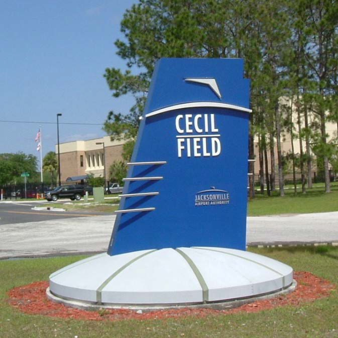 A blue sign shaped like an airplane wing with the words "Cecil Field Jacksonville Airport Authority"