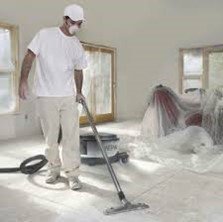 A person wearing all white and a mask vacuuming.