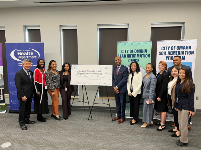 A group stands for a photo next to a large, ceremonial check during a ceremony in a conference hall.