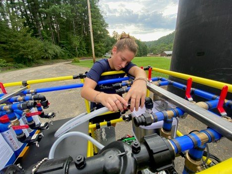 A light-skinned woman connects a hose to the WOW Cart system.