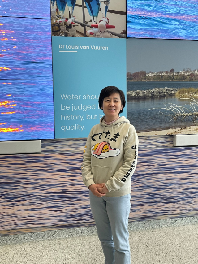 EPA researcher Yongping Yuan smiling posing in front of a scientific exhibit