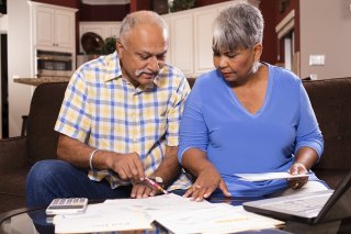 Couple on a couch going through utility bills.