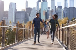 Family walking across a bridge with a city backdrop