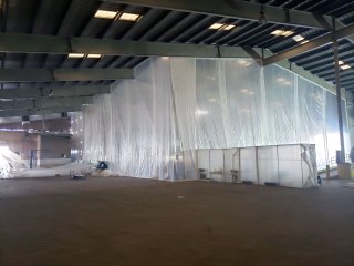 Interior of Finished Lead Building with steel truss roof with vertical plastic sheeting dividing a portion of the interior