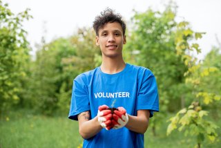 A young man holds a seedling to be planted.