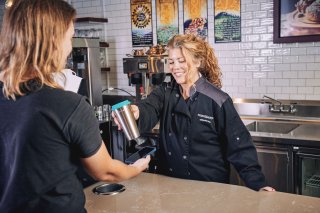 A woman scanning a stainless steel cup at a checkout counter