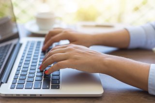 Close-up image of hands typing on a laptop keyboard