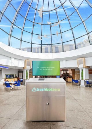 A recycling bin with a screen located in an open hallway