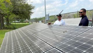 Administrator Regan standing in front of a collection of solar panels