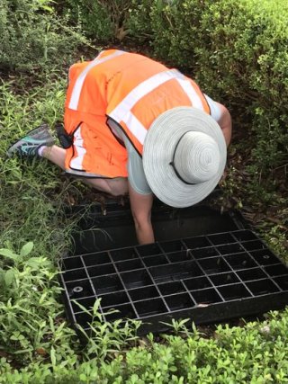 Worker reaching into drain.