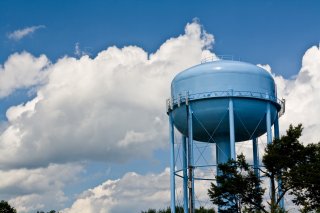 Blue water tower against blue sky.