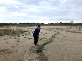 Worker digging a runnel by hand to drain surface water.