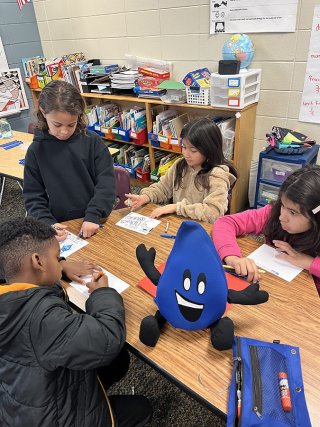 Children using writing utensils in a classroon.