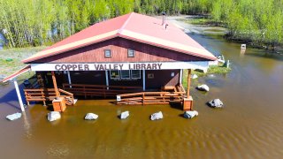 Flooding around red roofed building Copper Valley Library