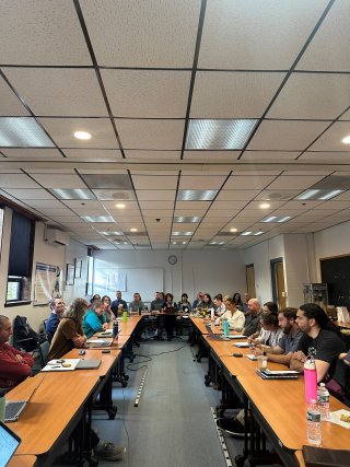 A large group sits at a U-shaped table.