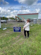 Woman standing next to a sign that reads "Bona Fide Prospective Purchaser"